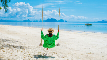 woman on the beach of the tropical Island Naka Island near Phuket Thailand, a woman on a swing on...