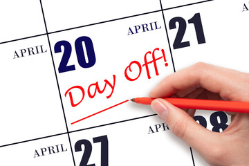 Hand writing text DAY OFF and drawing a line on calendar date 20 April. Vacation planning concept.