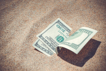 Money dollars half covered with sand lie on beach close-up. Dollar bills partially buried in sand. Three hundred dollars buried in sand on sea ocean beach Concept finance money holiday relax vacation