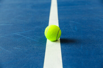 Summer sport concept with tennis ball on white line on hard tennis court blue color. Flat lay, top...