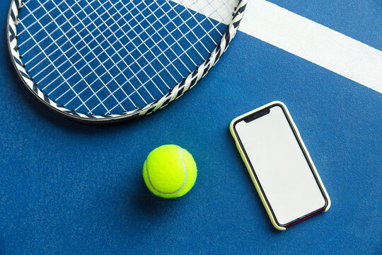 A tennis ball, a racket and a mobile phone with a put screen lie on a blue background. The concept of advertising a tennis club or ordering services