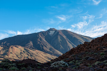 Panoramic view on volcano Pico del Teide after sunrise, Mount El Teide National Park, Tenerife, Canary Islands, Spain, Europe. Volcanic terrain. Looking from Paradores Canadas. Hiking trail in shadow