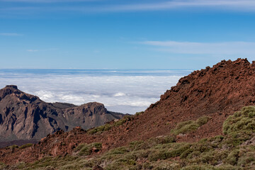 Hiking trail over volcanic terrain leading to summit of volcano Pico del Teide, Mount Teide National Park, Tenerife, Canary Islands, Spain, Europe. Valley and Atlantic Ocean is covered with clouds