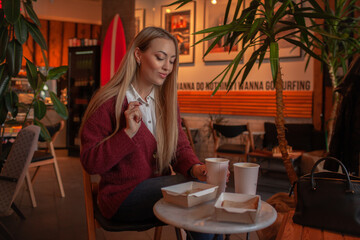 Pretty blond woman sit in cafe and eat testy sandwich with vegetables for breakfast in eco lunch box