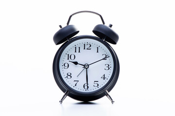 Black round metallic retro alarm clock isolated on white background. The clock shows daytime...