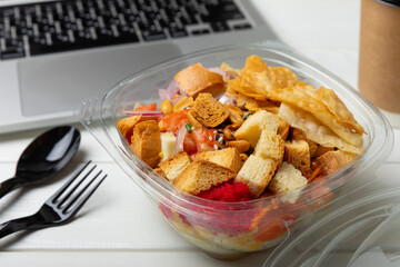Office work, lunches and home delivery. Poke with seafood and funchose on a white table with a laptop and a blank screen. Food delivery concept.Japanese food.Copy space. Place for text.