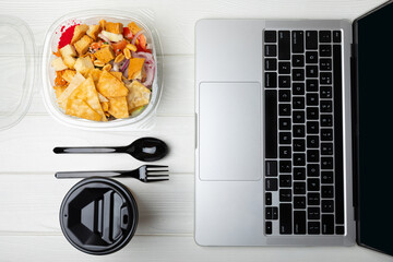 Office work, lunches and home delivery. Poke with seafood and funchose on a white table with a laptop and a blank screen. Food delivery concept.Japanese food.Copy space. Place for text.