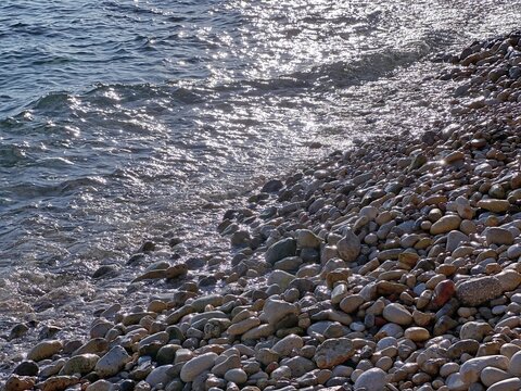 Shiny sea waves on pebbly beach.