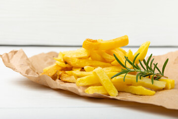French fries on a wooden background. Fast food. Baked homemade potatoes with rosemary. Harmful food. Place for text. Copy space.