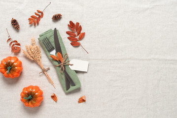 Autumn table setting place with cutlery and pumpkins, beige textile linen background. Concept,...