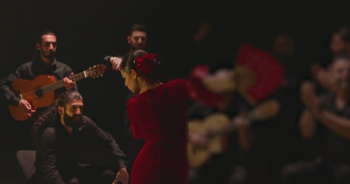 Beautiful stylish female artist dancing spanish style dance . Group of men playing on guitar and applauds to the dancer woman . Concept footage of spanish traditional culture . Waving cloth of skirt