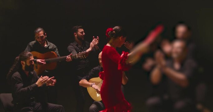 Beautiful stylish female artist dancing spanish style dance . Group of men playing on guitar and applauds to the dancer woman . Concept footage of spanish traditional culture . Waving cloth of skirt