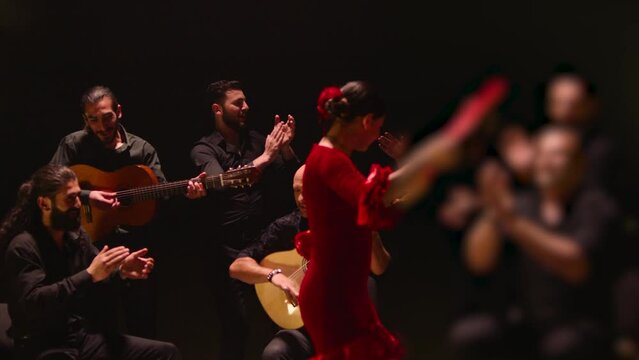 Beautiful stylish female artist dancing spanish style dance . Group of men playing on guitar and applauds to the dancer woman . Concept footage of spanish traditional culture . Waving cloth of skirt 
