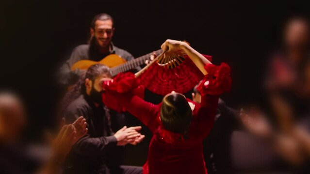 Beautiful stylish female artist dancing spanish style dance . Group of men playing on guitar and applauds to the dancer woman . Concept footage of spanish traditional culture . Waving cloth of skirt 