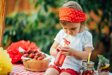 Lemonade Stand. Adorable little girl trying to sell lemonade. strawberry lemonade with ice and mint as summer refreshing drink in jars. Cold soft drinks with fruit. Child drinking smoothie in jar