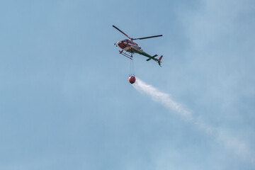 Hélicoptère pompier chargé d'une réserve d'eau intervenant sur le lieu d'un incendie de forêt