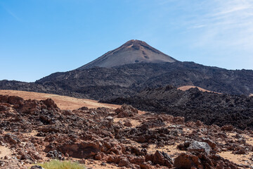 Fototapeta na wymiar Hiking trail over volcanic desert terrain leading to summit of volcano Pico del Teide, Mount Teide National Park, Tenerife, Canary Islands, Spain, Europe. Solidified lava, ash, pumice along the way