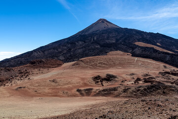 Fototapeta na wymiar Hiking trail over volcanic desert terrain leading to summit of volcano Pico del Teide from Pico Viejo, Mount Teide National Park, Tenerife, Canary Islands, Spain, Europe. Solidified lava, ash, pumice