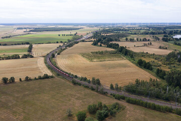 Güterzug fährt in der Kurve durch Getreidefeld, Luftaufnahme, Deutschland