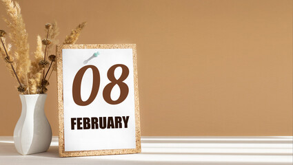 february 8. 8th day of month, calendar date.White vase with dead wood next to cork board with numbers. White-beige background with striped shadow. Concept of day of year, time planner, winter month