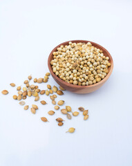 dried coriander seeds in the wooden bowl, isolated on white background