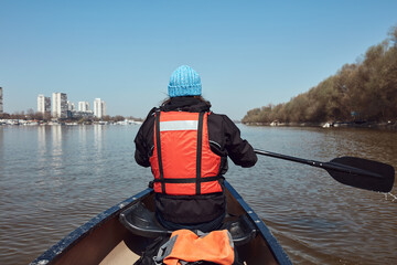 Man paddling in a canoe on a Danube river in urban area, small recreational escape, hobbies and...