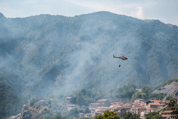 Hélicoptère pompier chargé d'une réserve d'eau intervenant sur le lieu d'un incendie de forêt