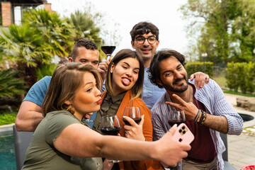 Happy group of Friends taking selfie while toasting red wine - Group of happy friends taking selfie using mobile smart phone camera - Young people having fun a drinking red wine outdoor