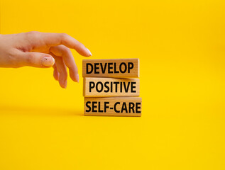 Develop positive self-care symbol. Concept words Develop positive self-care on wooden blocks. Beautiful yellow background. Businessman hand. Business and Develop positive self-care concept. Copy space