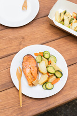 Salmon grilled fish with grilled vegetables in eco disposable tableware. Picnic in park. Vertical orientation. Tasty food. Seafood flat lay. 