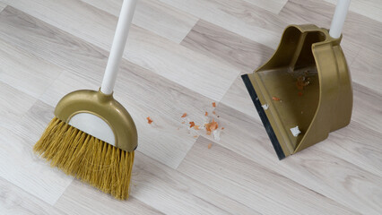 broom brush and scoop sweeping dirt off floor laminate