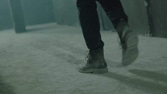 Close up of male legs in black boots . Rear back view of unknown man walking inside dark maze. Man  room, corridor. Footage of mystical video. Shot on ARRI ALEXA Cinema Camera in slow motion