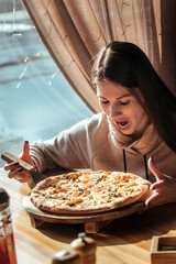 beautiful young girl with appetite eats pizza in a cafe