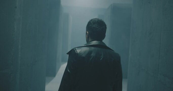 Rear back view of unknown man walking , standing or running inside dark maze. Dark corridor with concrete walls . Footage of mystical video. Shot on ARRI ALEXA Cinema Camera in slow motion  