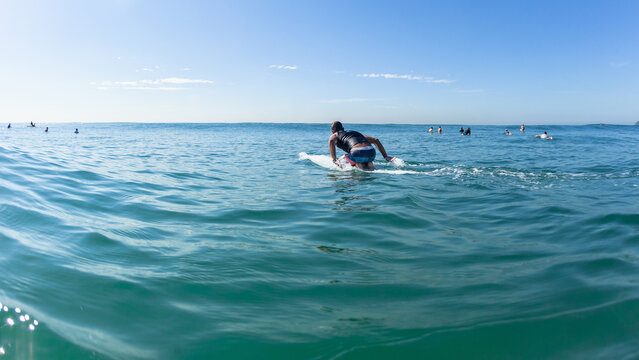 Surfer Paddling Long Surfboard Board Ocean Towards Blue Sky Horizon.