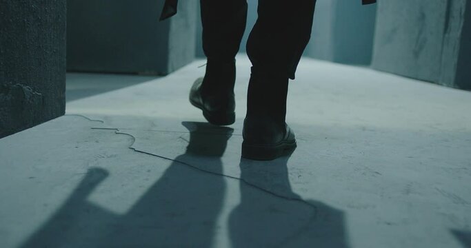 Close up of male legs in black boots . Rear back view of unknown man walking inside dark maze. Man  room, corridor. Footage of mystical video. Shot on ARRI ALEXA Cinema Camera in slow motion