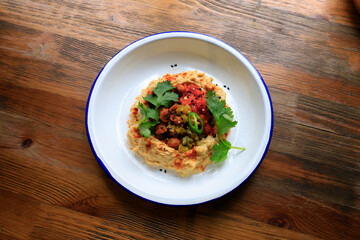 Hummus with chickpeas on white plate on wooden table. Top view, flatlay.