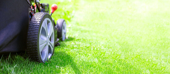 Template mock-up for the presentation of garden tools- modern lawn mower on green grass and copy space for your advertisement