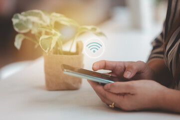 Woman hand using smart phone with wifi icon abstract background at coffee shop with colorful bokeh...