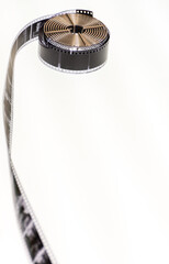 Coil of film with a section of unrolled film showing individual frames on a white background....
