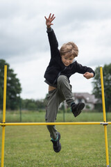 Young boy jumps up over the obstacle