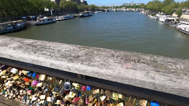 Love padlocks on a bridge with a tourist boat out of focus, Seine river in Paris. France, Europe.