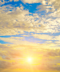 Beautiful sky with a bright sunset (rise) of the sun and light clouds. Vertical photo.