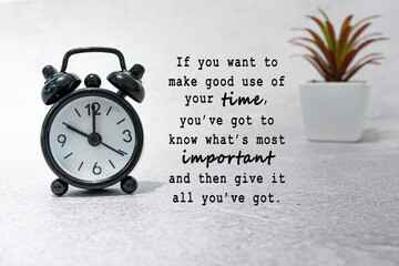 Motivational quote with black alarm clock set at 10 o'clock on the desk.