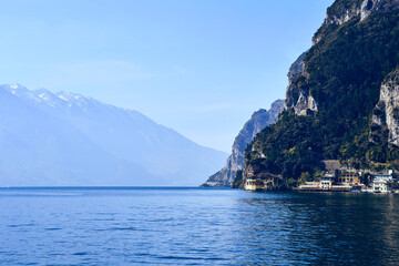 Fototapeta premium Garda lake viev on the open clean water surface with alpine mountain around and blue sky on the background