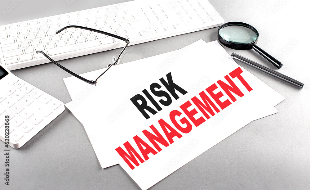 Aufkleber risk management text on a paper with keyboard, calculator on grey background