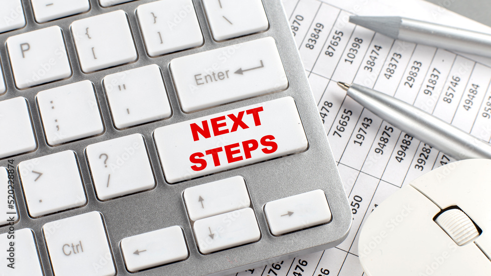 Poster next steps text on a keyboard wirh chart and pencil