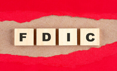 FDIC word on wooden cubes on red torn paper , financial concept background