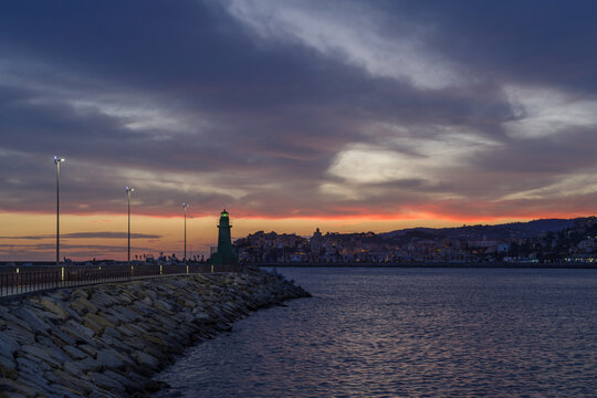 Dramatic colorful clouds at sunset with cityscape silhouette, Imperia, Liguria, Italy