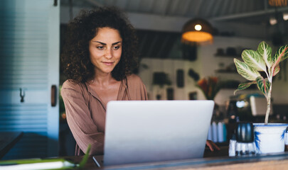 Skilled Caucasian woman spending time for social networking on modern laptop computer using WIFI...